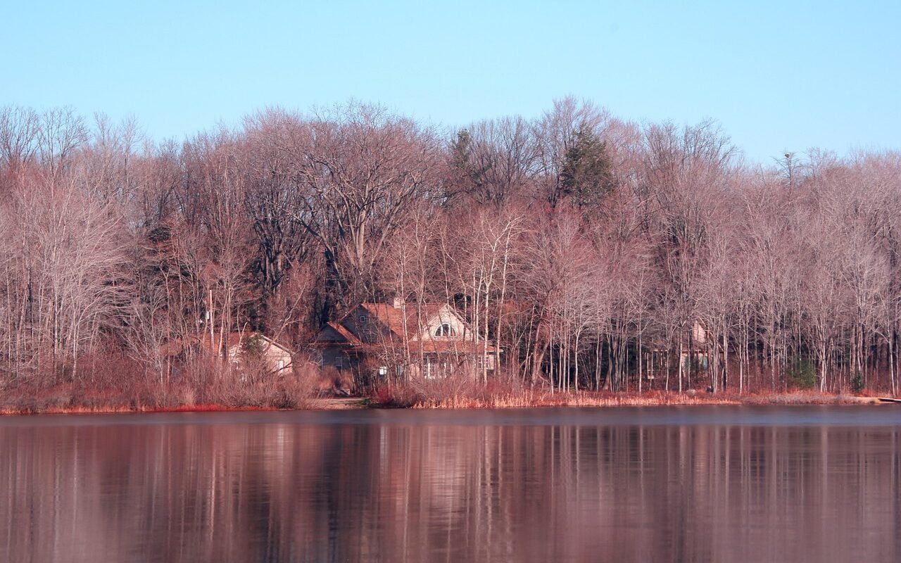 A serene view of michigan cottage country with a cozy cabin by the lake