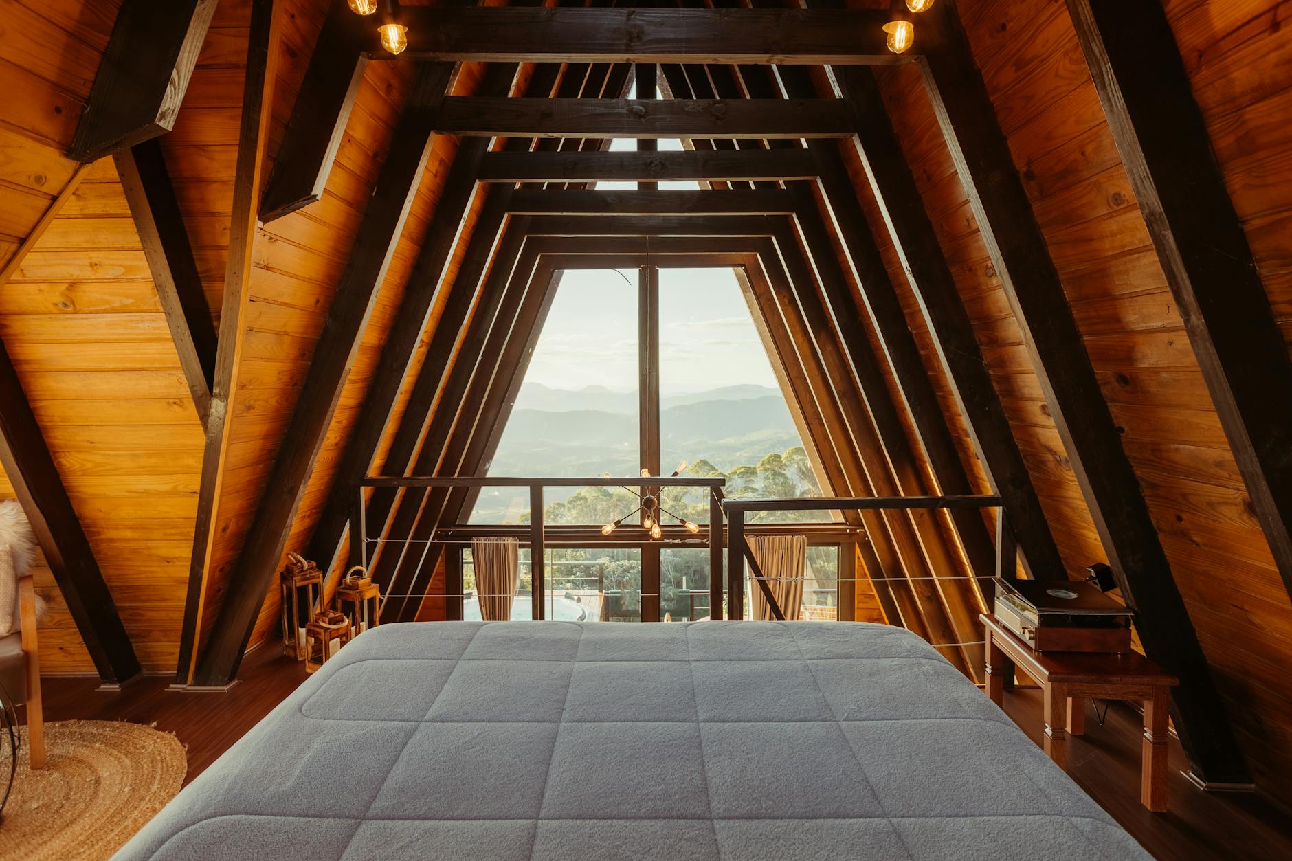 Wide bed in a luxury wooden cabin with a scenic mountain view