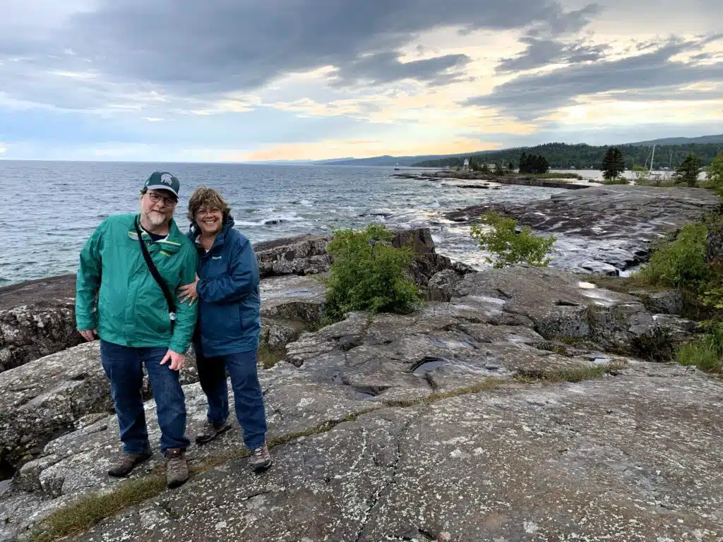 Two people on rocky shoreline.