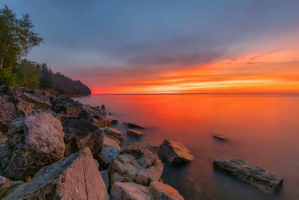 Serene sunset over rocky shoreline.