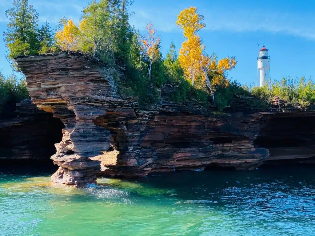 Lighthouse beside rocky shoreline and trees