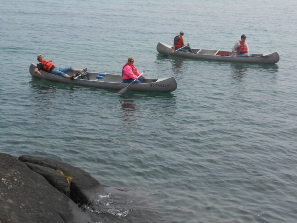 Three people canoeing on water. - Great Lakes Islands to explore